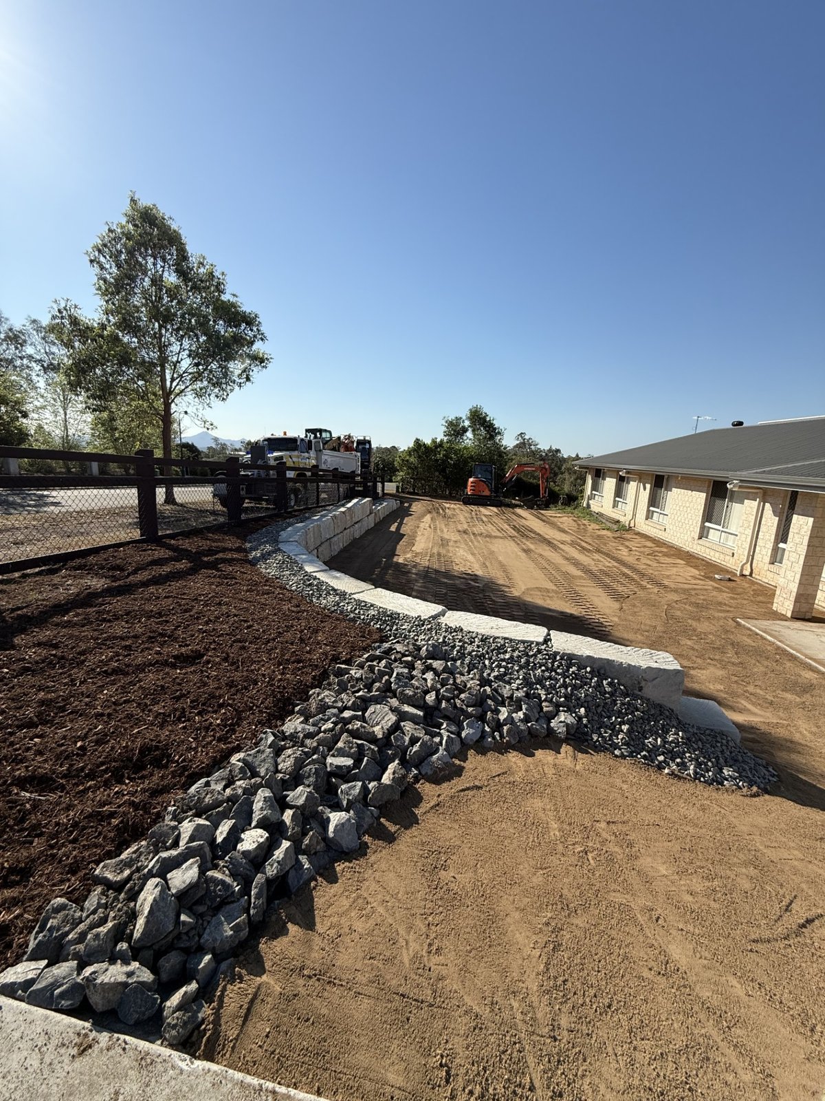 Hitachi excavator with grab placing sandstone blocks for retaining wall
